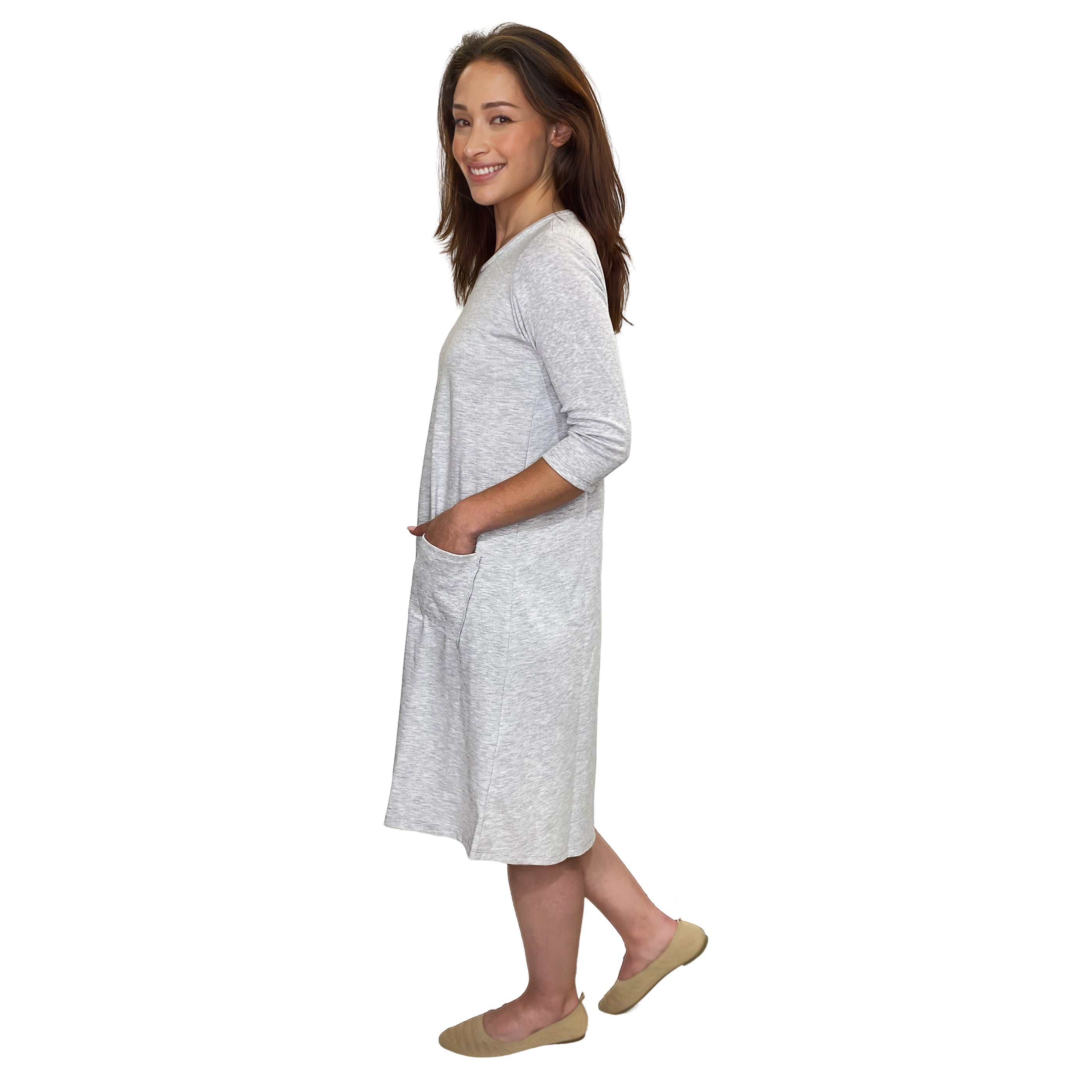 A woman modeling a light gray heathered three-quarter sleeve tunic dress with side pockets, shown from a side profile against a plain white background.