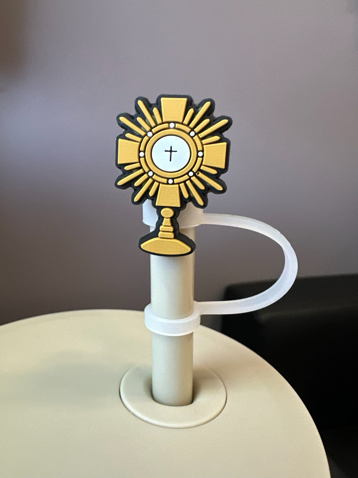 Gold monstrance on a white stand against a gray background