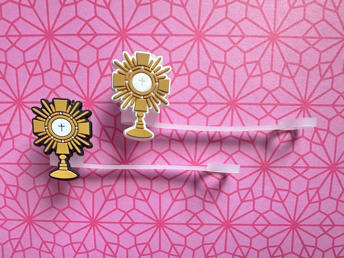Two gold religious symbols on a pink geometric patterned background