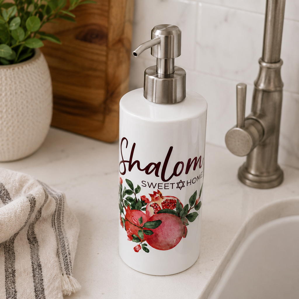 Soap dispenser with 'Shalom Sweet Home' text and fruit design on a bathroom counter.