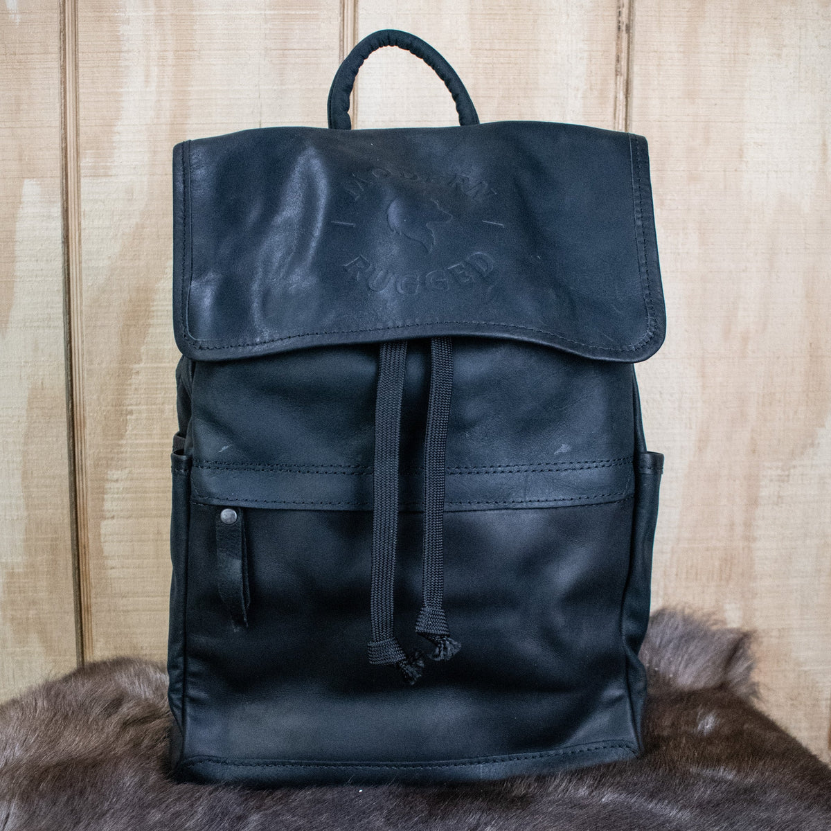 Black leather backpack on a wooden surface