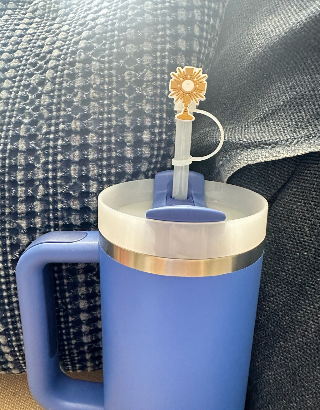 Blue mug with a gold rim and a sunflower-themed straw on a textured surface.