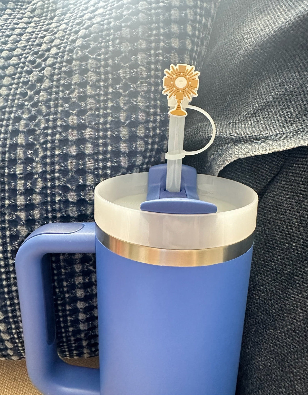 Blue mug with a gold rim and a sunflower-themed straw on a textured surface.