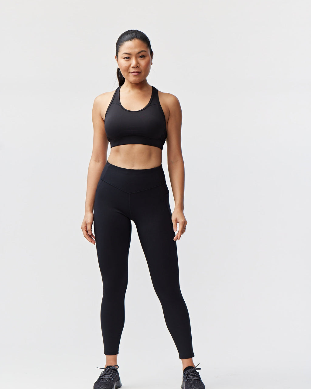 Woman wearing a black sports bra and leggings on a white background