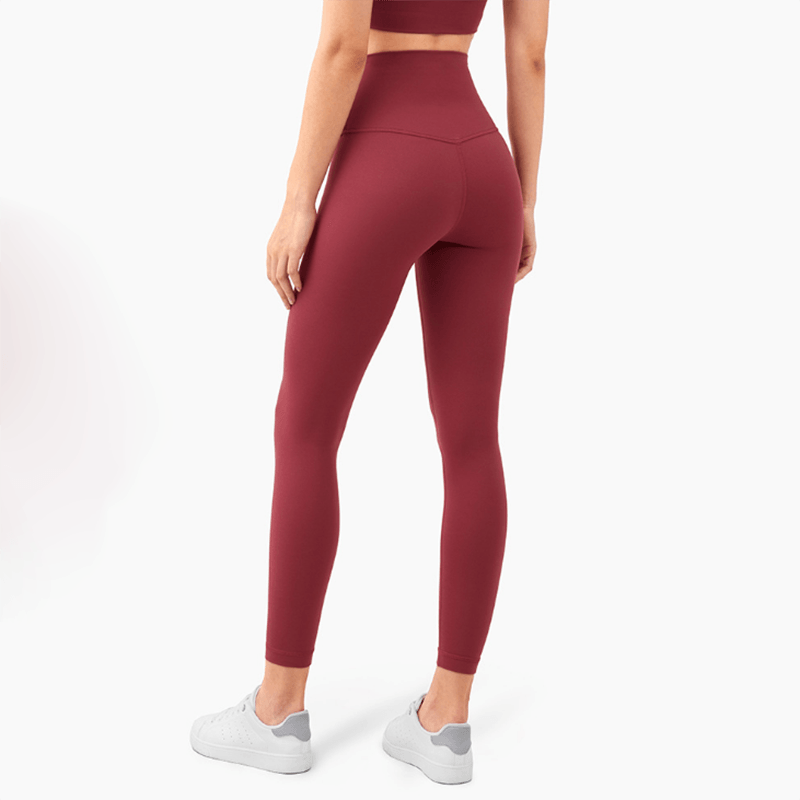 Person wearing maroon leggings and a matching top on a white background