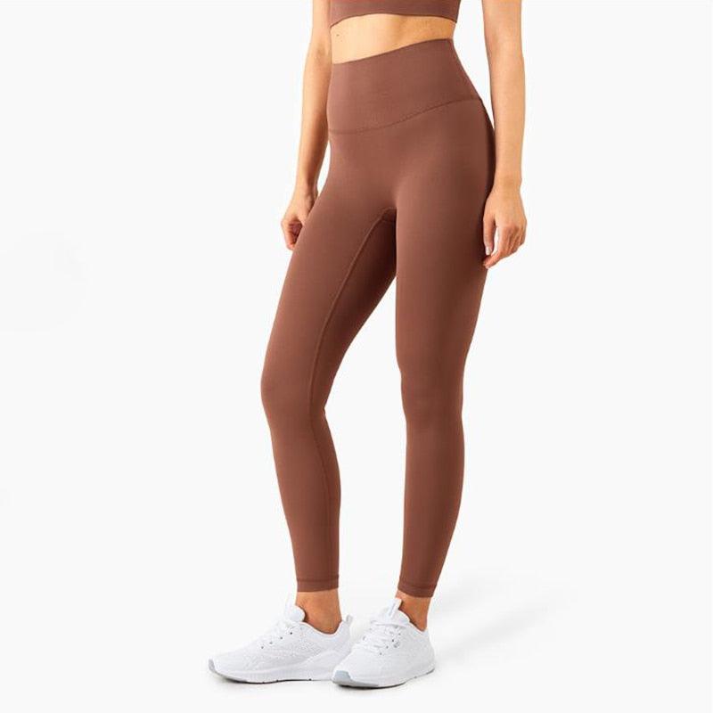 Person wearing brown leggings and white sneakers on a white background