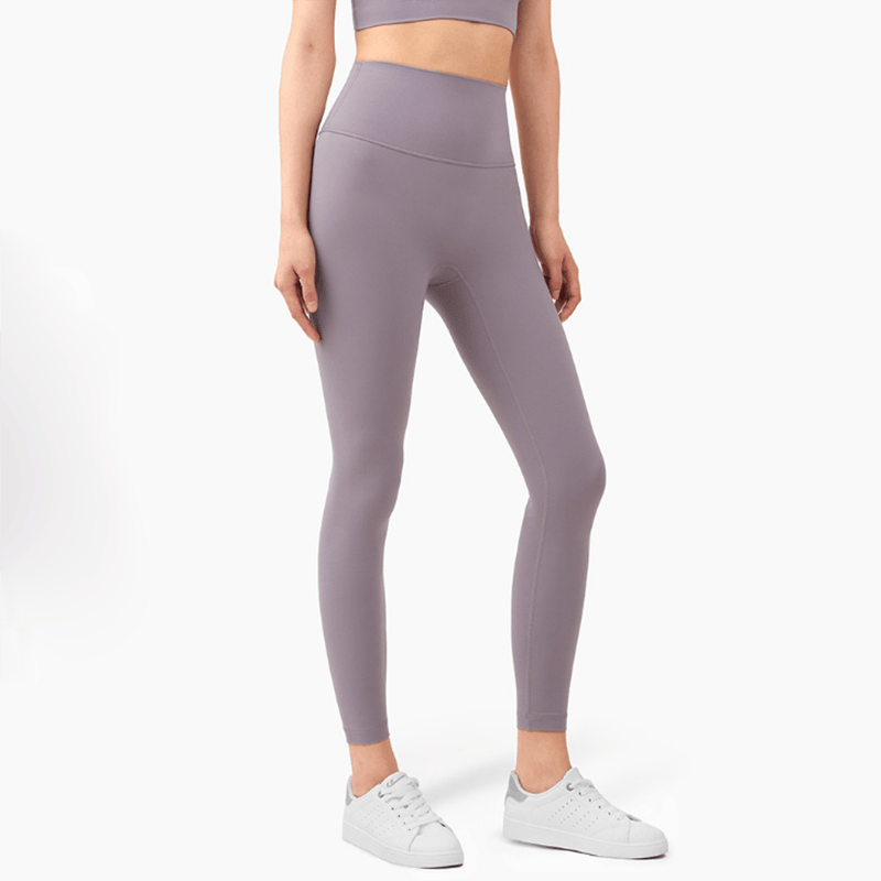 Person wearing purple leggings and a matching crop top on a white background