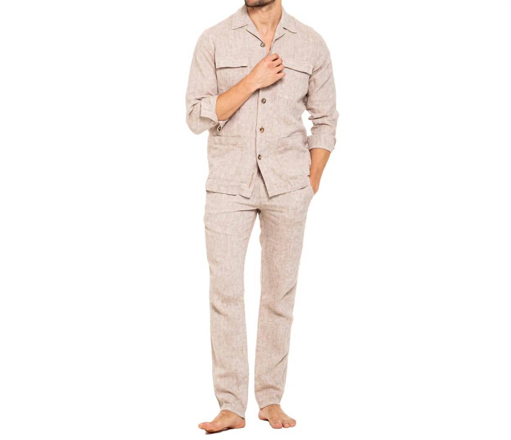 A man modeling a light beige linen two-piece pajama set consisting of a long-sleeve button-up shirt and matching pants, shown against a plain white background.