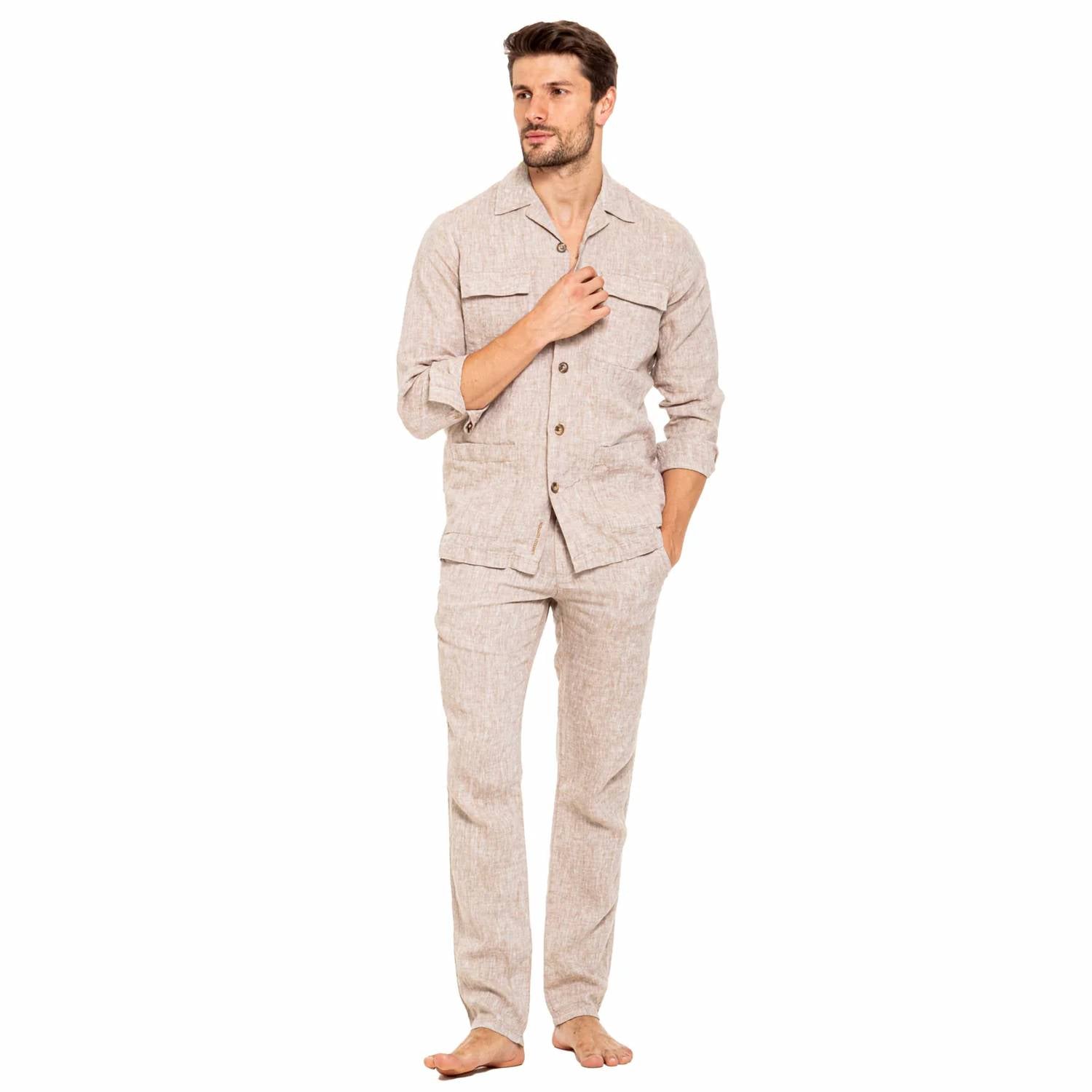 A man modeling a light beige linen pajama set consisting of a long-sleeve button-up shirt and matching pants, standing against a solid white background.