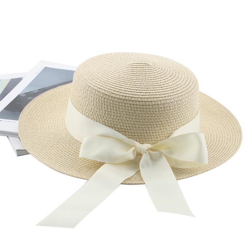 Beige straw hat with a white ribbon on a white background