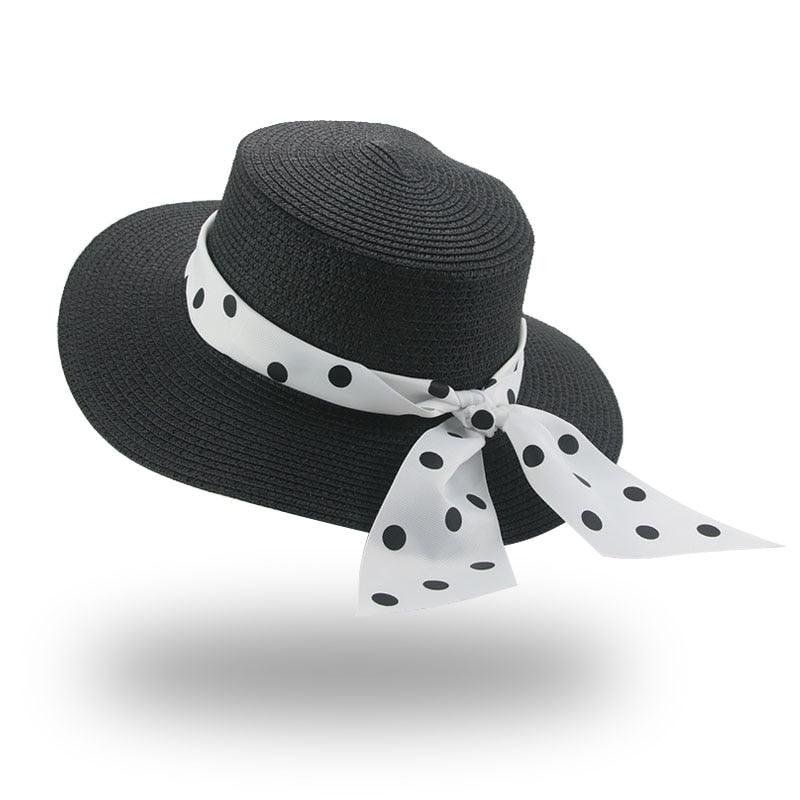 Black straw hat with a white polka dot ribbon on a white background