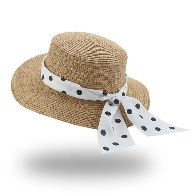 Beige straw hat with a white polka dot ribbon on a white background