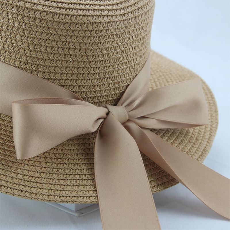 Beige straw hat with a bow on a light blue background
