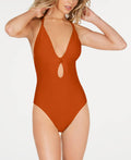 A woman modeling a rust-orange one-piece swimsuit with a halter neckline, deep V-front cutout, and keyhole detail at the center bust, photographed against a clean white studio background.