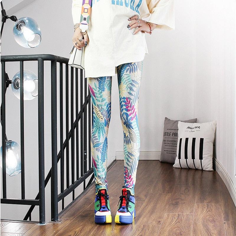 Person wearing colorful floral leggings and multicolored shoes in a room with a black metal railing and white walls.