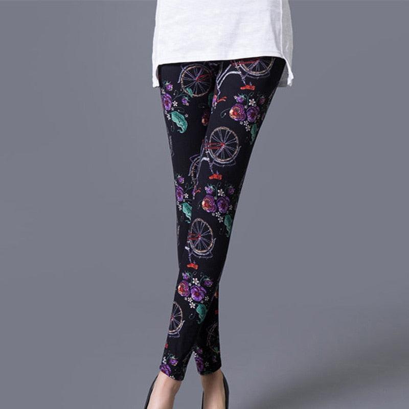 Black leggings with floral and bicycle pattern worn by a person on a gray background