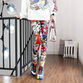 Person wearing colorful pants and shoes in a room with a black metal railing and light fixtures.
