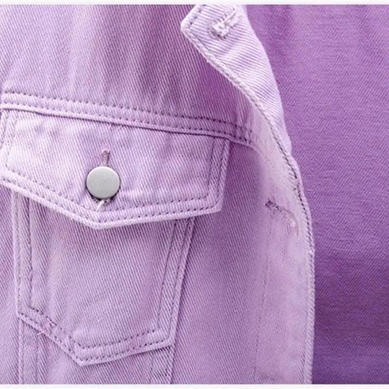Close-up of a purple denim jacket with a button and pocket detail.