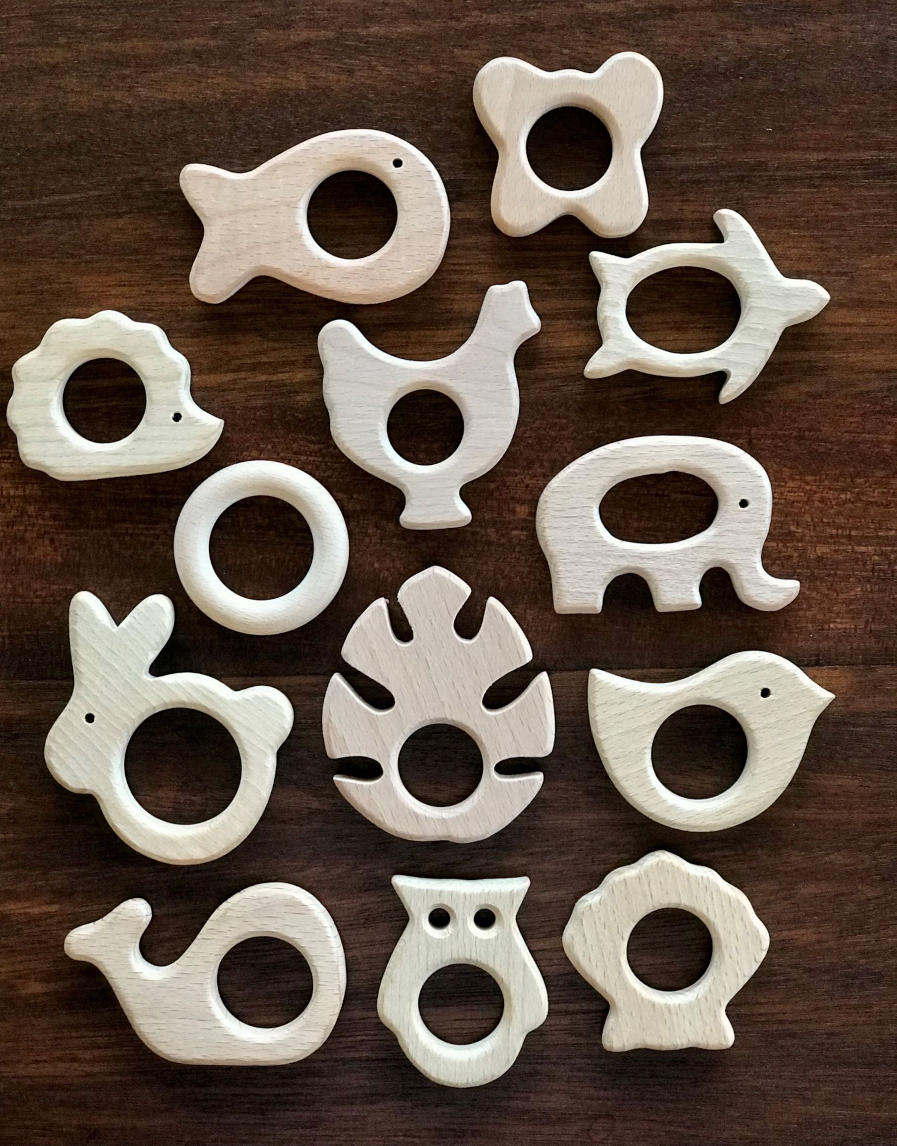Set of white animal-shaped wooden teethers on a dark wooden surface