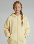 Young girl wearing a light yellow hoodie against a plain background